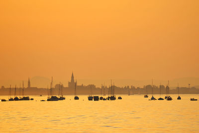 Sailboats in lake during sunset silhouette in front