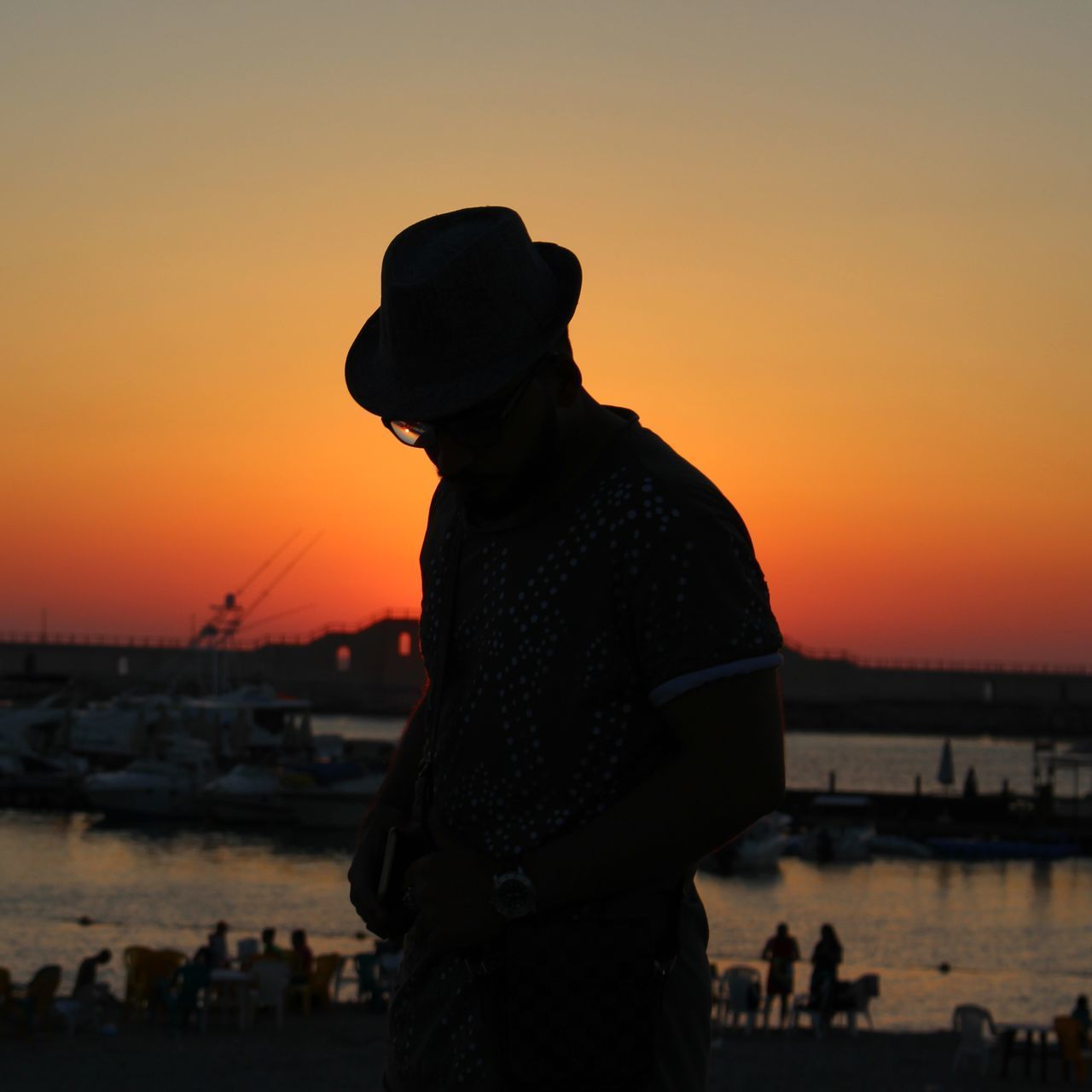 SILHOUETTE MAN STANDING AGAINST SEA DURING SUNSET