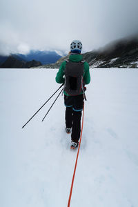 Rear view of woman walking on snow against sky