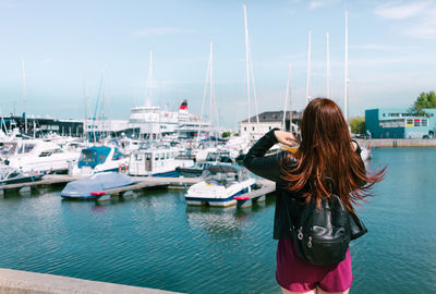 Woman standing at harbor against sky