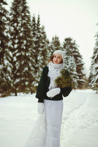 Redhead beautiful woman in green sweater and white gloves walking in the frozen winter forest