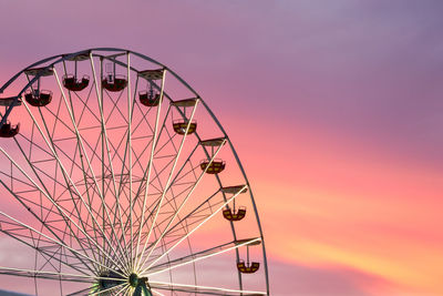 Low angle view of ferris wheel against sky at sunset