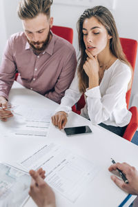 Young couple discussing over document while real estate agent explaining 