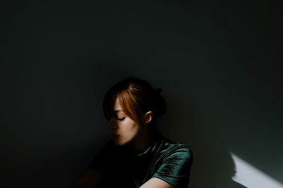 Young woman looking away against black background