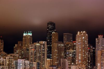 Illuminated modern buildings against sky in city