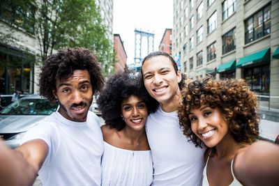 Portrait of smiling friends standing on street in city