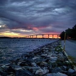 Bridge over sea against cloudy sky