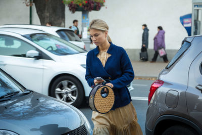 Woman standing by car on road