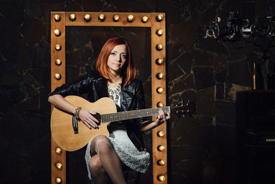 Portrait of young woman playing guitar