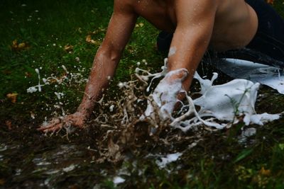 Midsection of shirtless man on muddy field