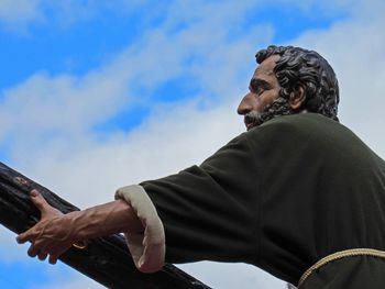 Low angle view of man sitting against blue sky