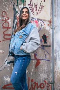 Portrait of smiling man standing against graffiti wall