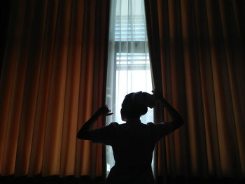 Silhouette woman looking through window