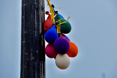 Low angle view of balloons hanging against blue sky