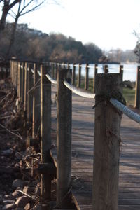 Wooden post on fence by field against sky