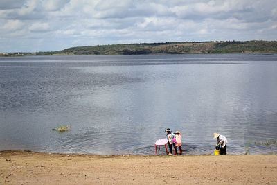 Rear view of people at beach against sky