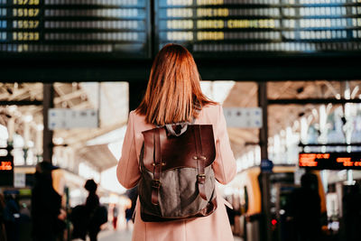 Rear view of woman wearing backpack standing on railroad station