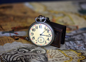 Close-up of pocket watch on map