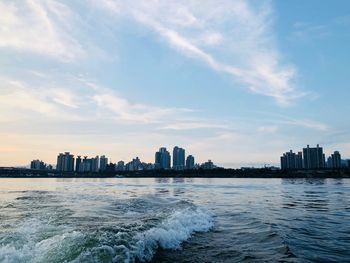 Sea by buildings against sky in city