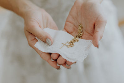 Midsection of bride holding cross pendant