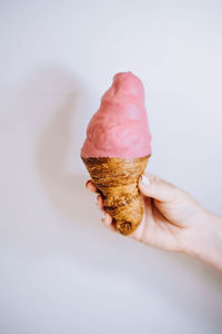 Person holding ice cream cone against white background