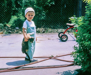 Full length of boy holding cat while standing in yard