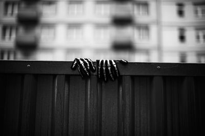 Low angle view of gloves on wooden fence against building