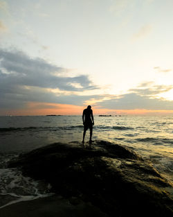 Silhouette man standing on beach against sky during sunset