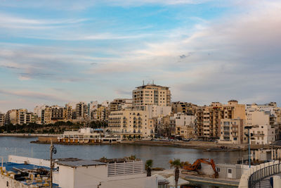 Buildings by sea against sky in city