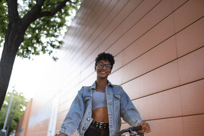 Young woman wearing denim jacket near wall