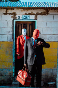 Rear view of female friends standing against wall