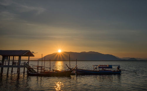 Silhouette boats in sea against sky during sunset