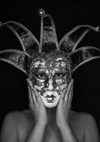 Close-up of woman wearing mask against black background
