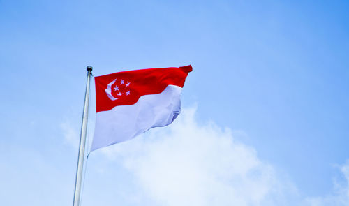 Low angle view of flag waving against blue sky