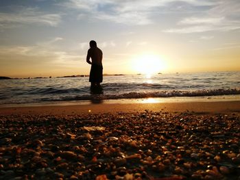 Silhouette man standing at beach during sunset