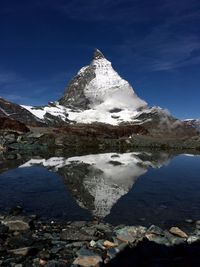 Idyllic shot of snowcapped mountain reflection in lake against blue sky