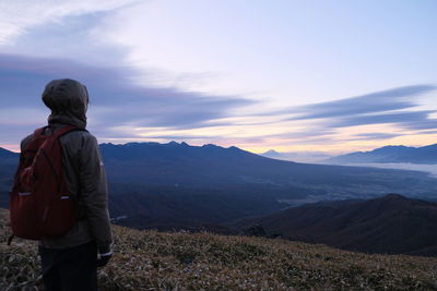 Rear view of man looking at mountains against sky