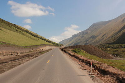 Road by mountains against sky