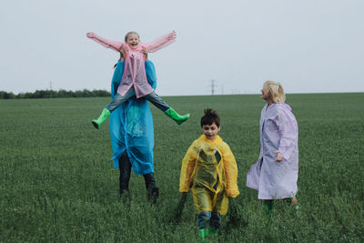 Full length of siblings walking on field