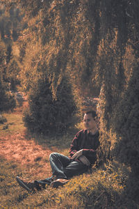 Man looking away while sitting at forest