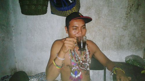 Full length portrait of a man drinking glass against wall