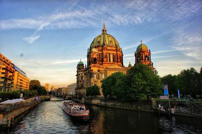 Boat in canal against buildings during sunset