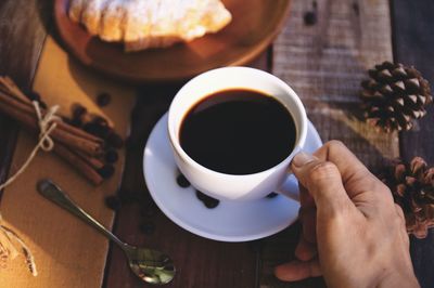 Cropped hand of woman holding coffee on table