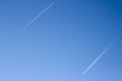 Low angle view of vapor trail against clear blue sky