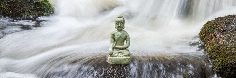 Buddha sculpture sitting in flowing water