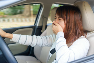 Woman yawning while sitting in car