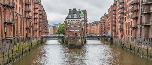 Canal amidst buildings in city against sky