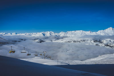 A chairlift rising out of a valley of clouds in les arcs