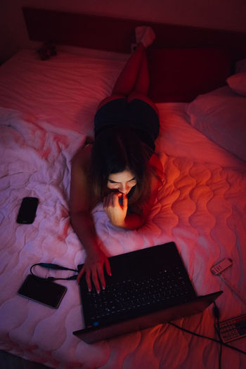 High angle view of young woman using laptop on bed at home