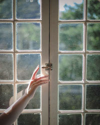 Close-up of hand looking through window